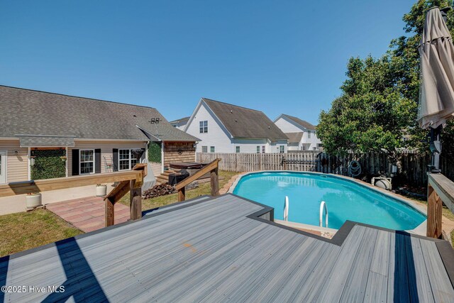 view of swimming pool with a wooden deck, a fenced in pool, and a fenced backyard