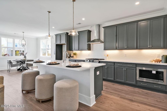 1348 Trisail Ter, Wilmington, NC 28412 - kitchen featuring stainless steel microwave, tasteful backsplash, wall chimney range hood, light countertops, and range