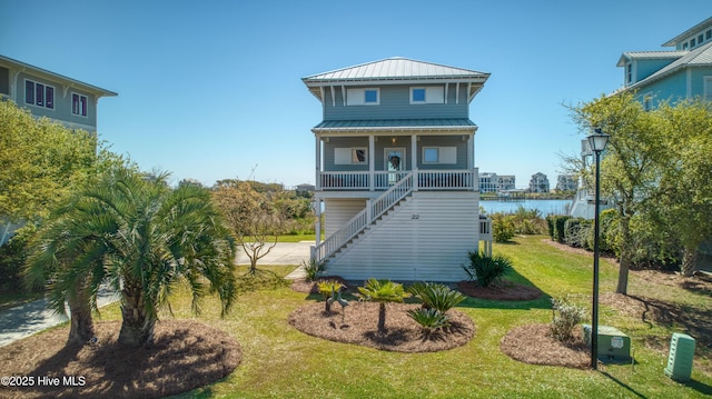 back of house with a porch, metal roof, stairway, a yard, and a water view
