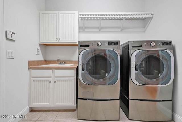 laundry room featuring baseboards, a sink, independent washer and dryer, cabinet space, and light tile patterned flooring