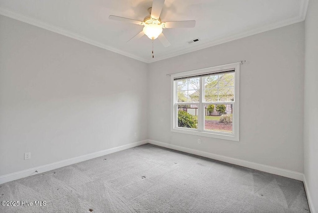 spare room featuring baseboards, ornamental molding, carpet floors, visible vents, and ceiling fan