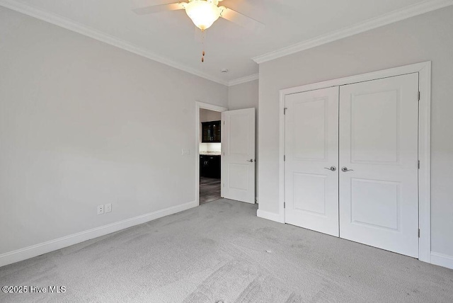 unfurnished bedroom with a closet, baseboards, ornamental molding, a ceiling fan, and carpet floors