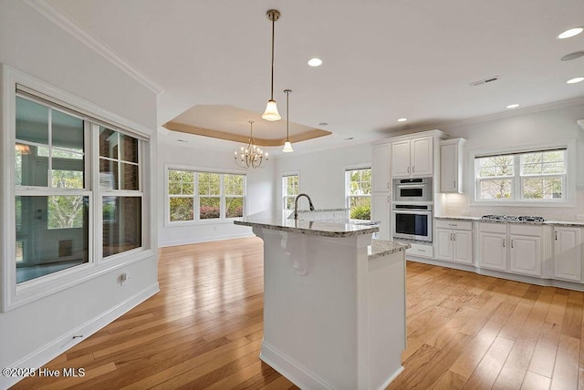 kitchen featuring plenty of natural light, light wood-type flooring, ornamental molding, and white cabinetry