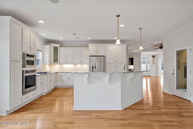 kitchen featuring white cabinets, crown molding, appliances with stainless steel finishes, and a breakfast bar