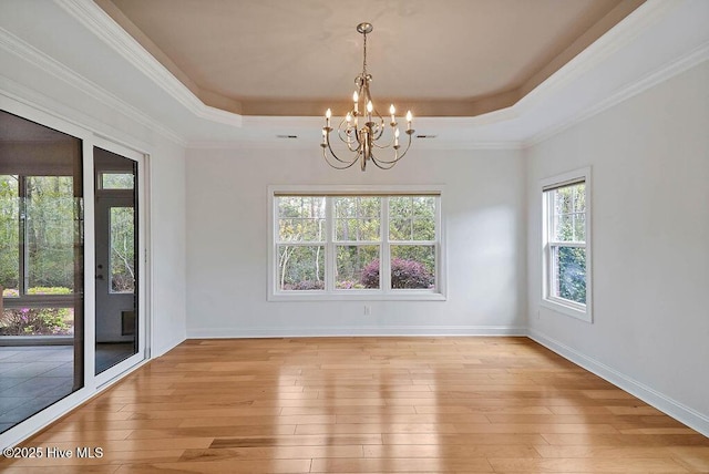 unfurnished dining area featuring a chandelier, light wood-type flooring, baseboards, and a raised ceiling