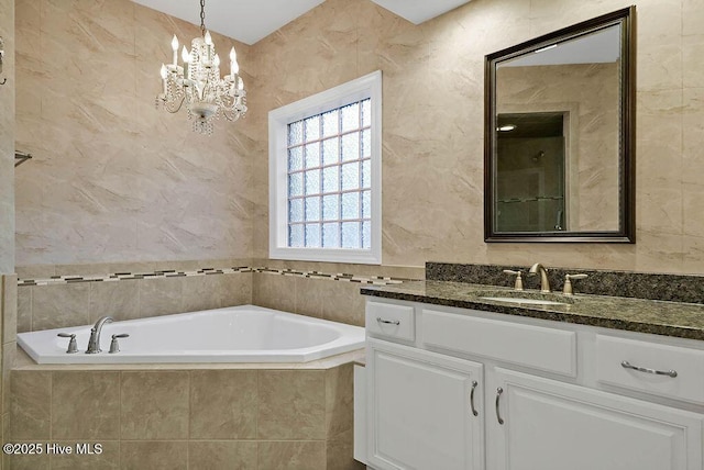 bathroom featuring a chandelier, vanity, and a bath