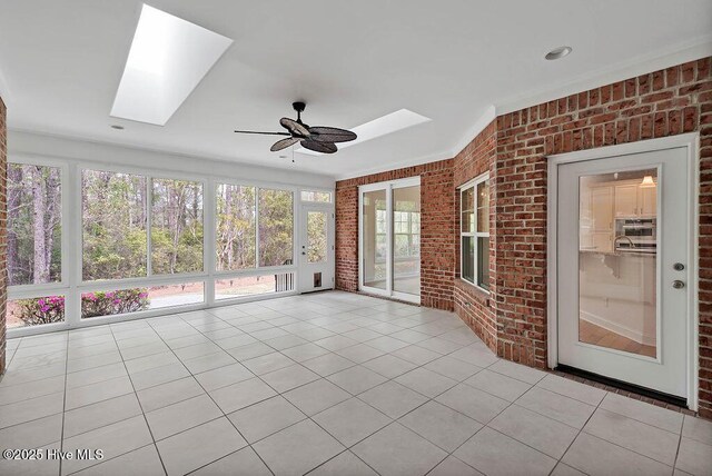 unfurnished sunroom with a skylight, plenty of natural light, tile patterned flooring, and brick wall