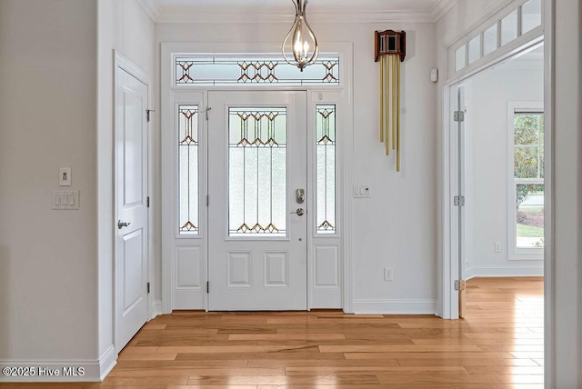 foyer with baseboards, light wood-type flooring, and crown molding