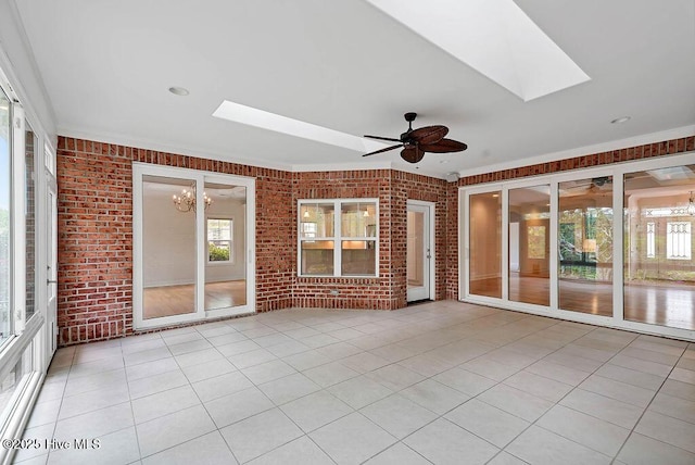 unfurnished sunroom featuring ceiling fan with notable chandelier and a skylight