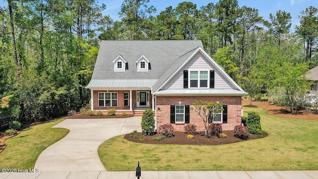 view of front facade with concrete driveway, a front yard, brick siding, and roof with shingles