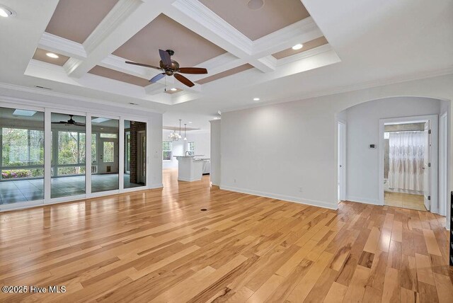 unfurnished living room featuring arched walkways, ornamental molding, beam ceiling, ceiling fan with notable chandelier, and coffered ceiling