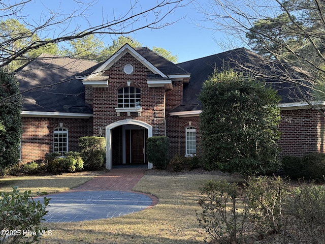 traditional home featuring brick siding and a shingled roof