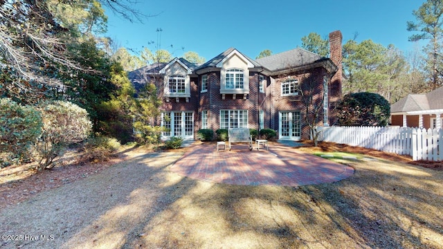 view of front of home with brick siding, a patio, french doors, and fence