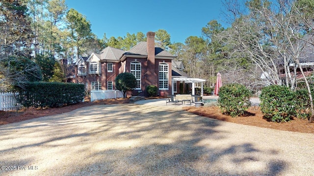 view of front of property with a patio, fence, brick siding, and a chimney
