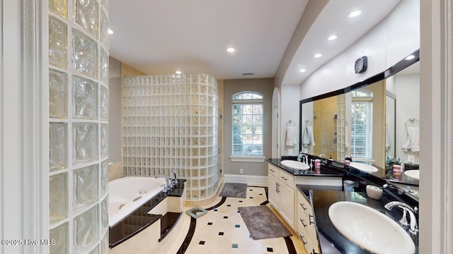 bathroom featuring double vanity, recessed lighting, a garden tub, and a sink