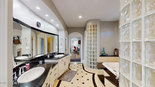 full bathroom with recessed lighting, a garden tub, and vanity