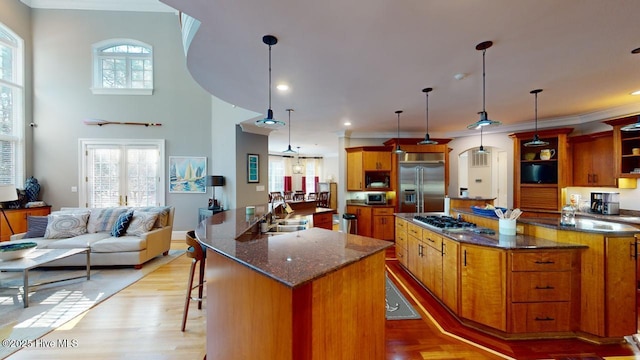 kitchen with a spacious island, built in appliances, light wood-style floors, plenty of natural light, and a sink