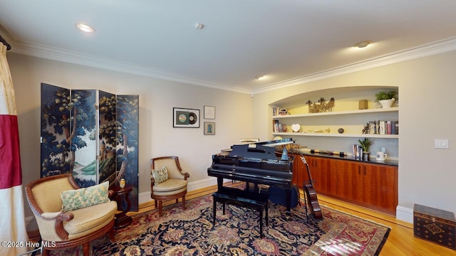sitting room featuring crown molding, built in shelves, wood finished floors, and baseboards