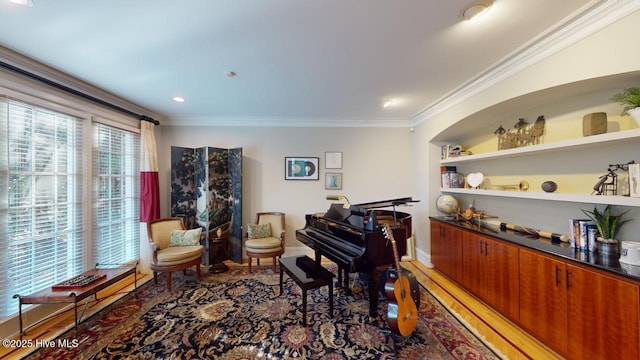 living area featuring baseboards, built in shelves, ornamental molding, and light wood finished floors