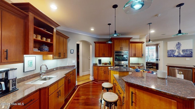 kitchen featuring arched walkways, a sink, crown molding, double oven, and a center island