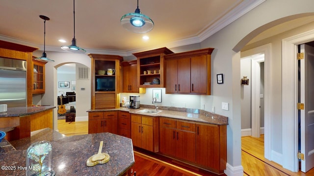 kitchen with a sink, open shelves, arched walkways, light wood-style floors, and crown molding