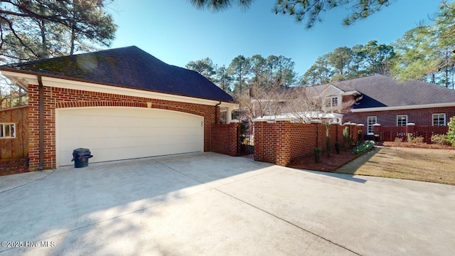 view of side of home with concrete driveway, a garage, fence, and brick siding