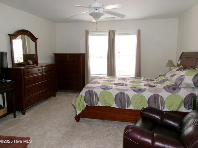 bedroom with visible vents, light colored carpet, and ceiling fan