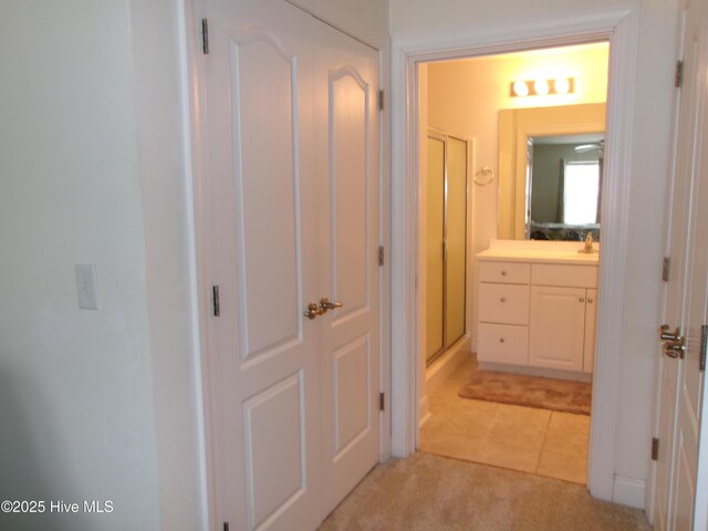 hallway featuring light tile patterned floors and light carpet
