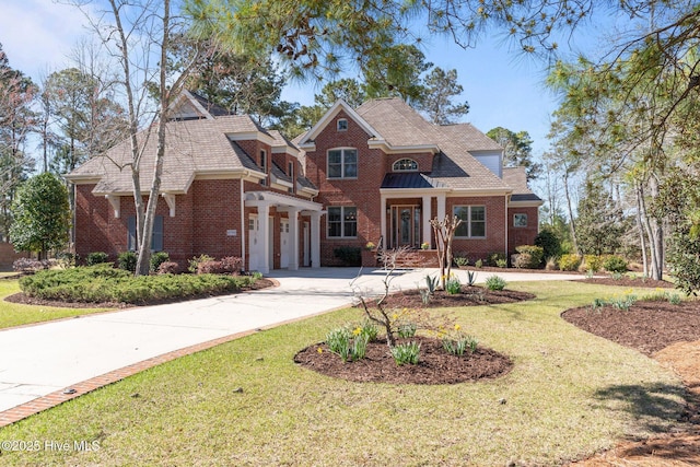 view of front of home featuring a front yard, brick siding, and driveway