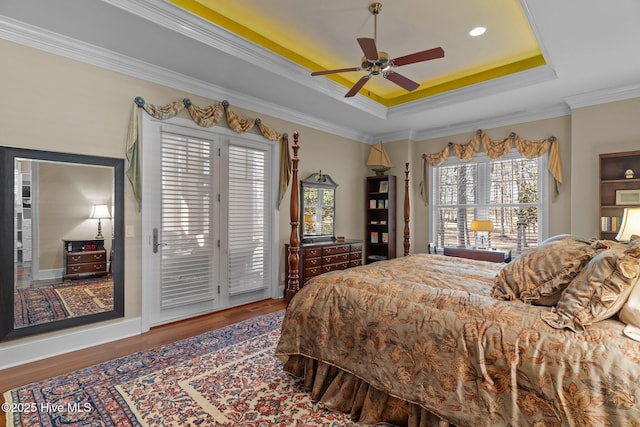 bedroom featuring wood finished floors, a tray ceiling, ceiling fan, access to exterior, and crown molding
