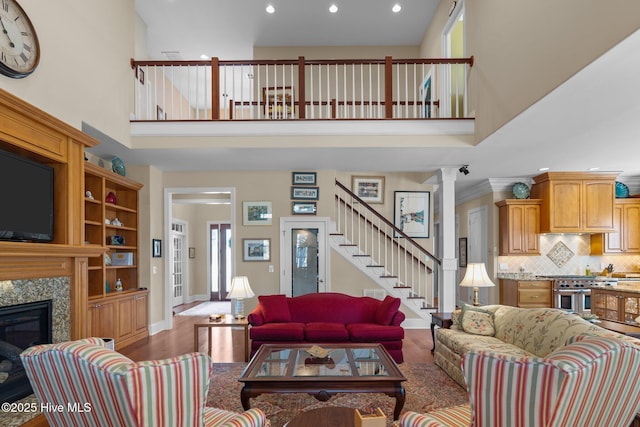 living room with wood finished floors, a high ceiling, a premium fireplace, baseboards, and stairs