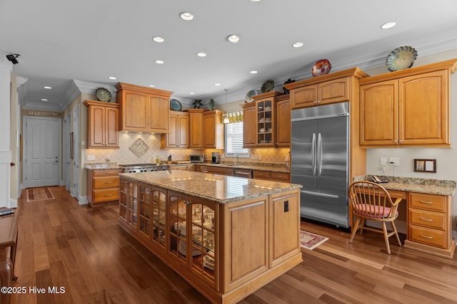 6790 Waterstone Xing SW, Ocean Isle Beach, NC 28469 - kitchen with stainless steel appliances, ornamental molding, glass insert cabinets, a kitchen island, and dark wood-type flooring