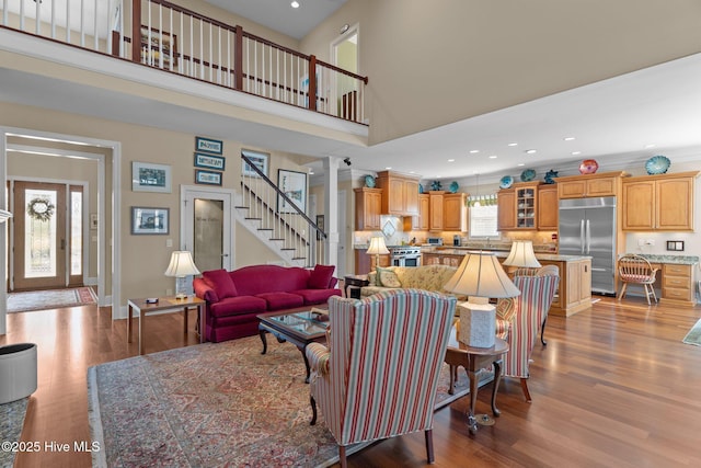 living room featuring stairs, a high ceiling, recessed lighting, and wood finished floors