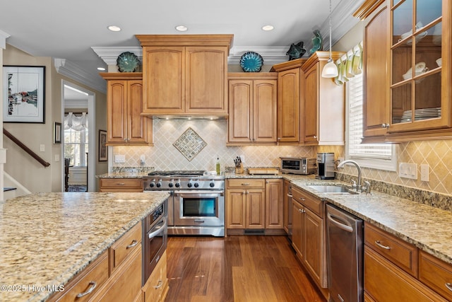 kitchen with a sink, light stone counters, glass insert cabinets, and stainless steel appliances