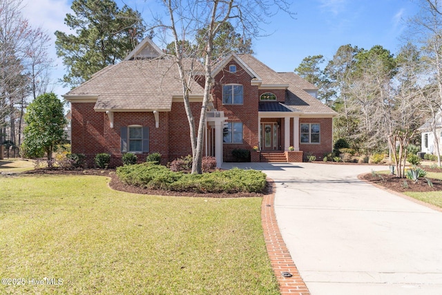 view of front of home featuring brick siding, concrete driveway, and a front lawn