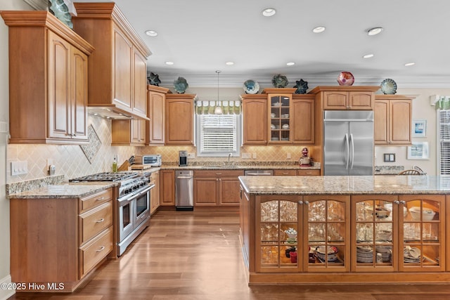 kitchen with a sink, appliances with stainless steel finishes, glass insert cabinets, and crown molding
