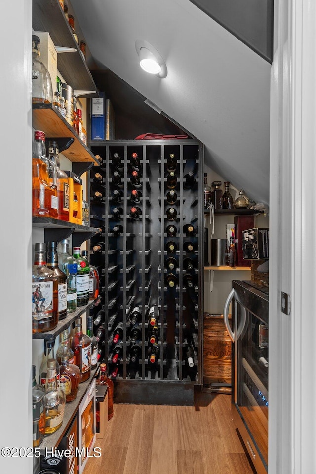 wine cellar featuring lofted ceiling, beverage cooler, and wood finished floors