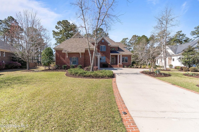 view of front of home with a front yard, concrete driveway, and brick siding
