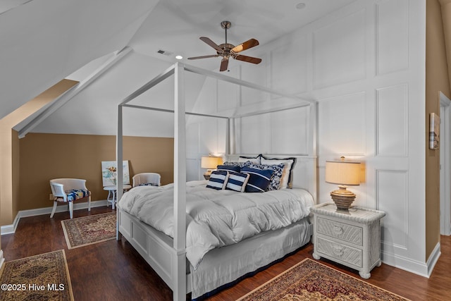bedroom featuring a decorative wall, wood finished floors, visible vents, and vaulted ceiling
