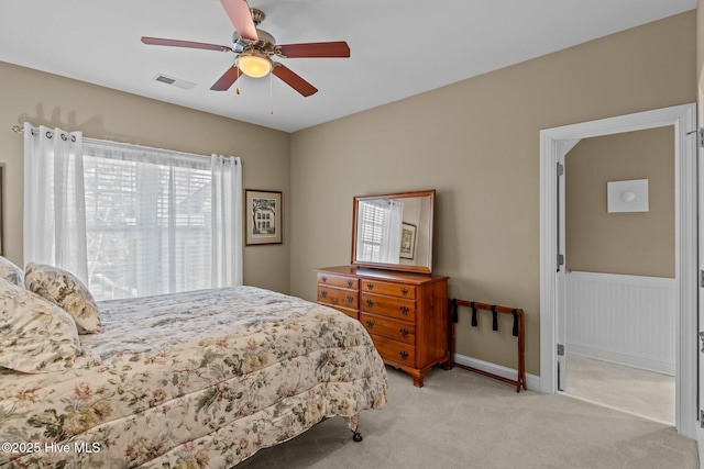 bedroom with visible vents, light carpet, wainscoting, baseboards, and ceiling fan