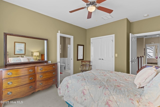bedroom featuring visible vents, connected bathroom, ceiling fan, light colored carpet, and a closet