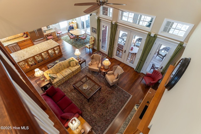 living area with french doors, a high ceiling, ceiling fan, and wood finished floors