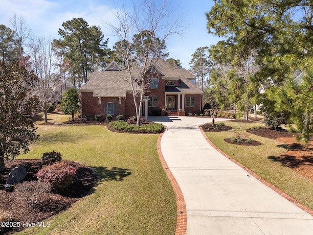 view of front of house featuring brick siding, concrete driveway, and a front lawn