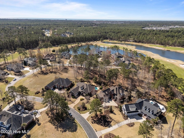 birds eye view of property with a wooded view, a water view, and a residential view