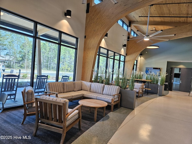 living room featuring beamed ceiling, high vaulted ceiling, arched walkways, wooden ceiling, and ceiling fan