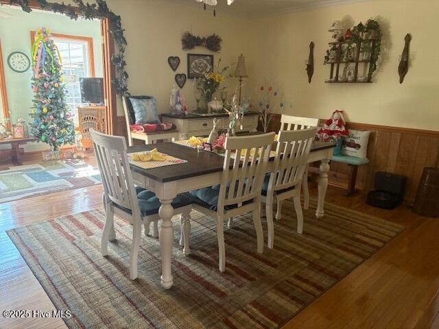 dining room featuring wooden walls, wood finished floors, and wainscoting