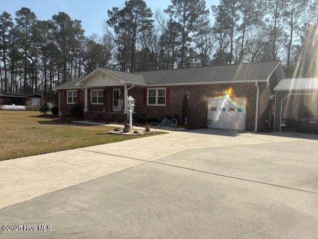 single story home featuring brick siding, concrete driveway, a front yard, and a garage
