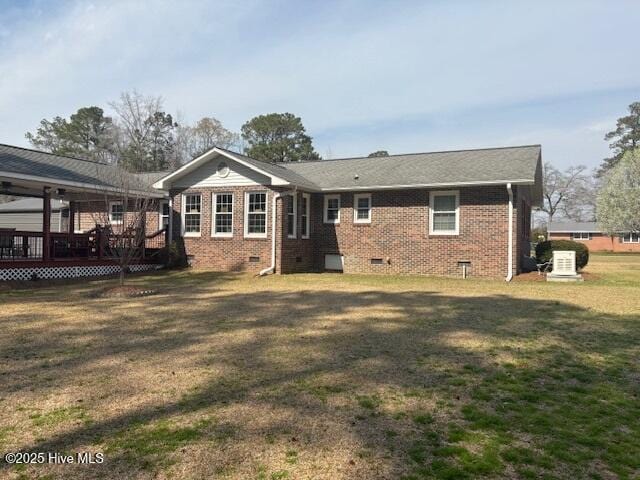 back of property featuring a deck, a yard, brick siding, and crawl space