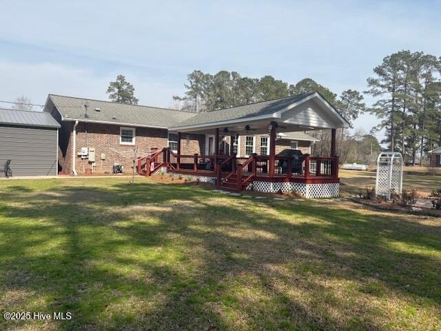 rear view of house with brick siding, a wooden deck, and a yard