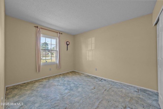 spare room with carpet flooring, a textured ceiling, and baseboards